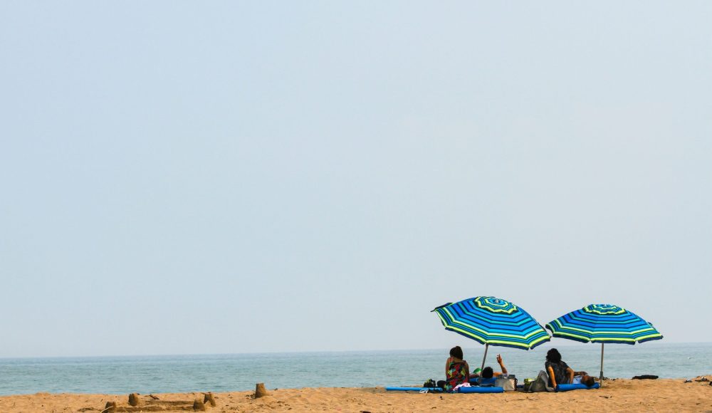 people lying on mat under green and blue umbrella during daytime